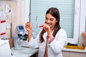 Optician repairing spectacles with tool in optical store photo