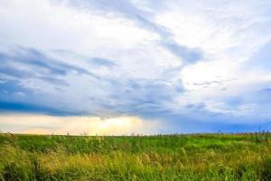 paisaje de campo verde con cielo azul y nubes tormentosas. foto