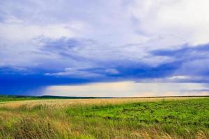 paisaje de campo verde con cielo azul y nubes tormentosas. foto