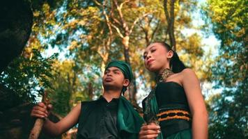 An Asian couple hangs out together in the forest while wearing a traditional green dress and talking to each other while enjoying the view video