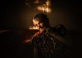 very old and tired wrinkled woman sitting on a sofa photo