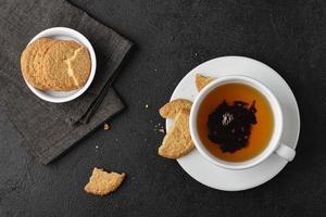 taza de té con galletas sobre fondo negro. foto