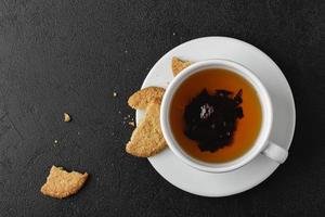 taza de té negro con galletas sobre fondo oscuro. foto