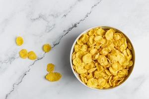 Corn flakes in white bowl on marble table. photo