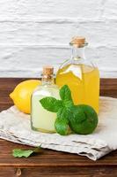 Lime and lemon syrups in a glass bottle with fruits and mint photo