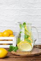 Lemonade with mint in jug and lemons in crate photo