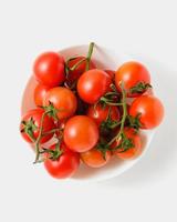 tomates cherry en un tazón sobre fondo blanco. foto