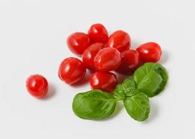 tomates cherry con albahaca verde sobre fondo blanco. foto