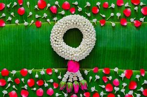Songkran festival background with jasmine garland and flowers on banana leaf background. photo