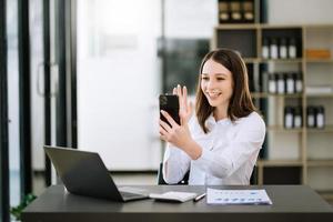 Asian business woman are delighted and happy with the work they do on their tablet, laptop and taking notes at the office. photo