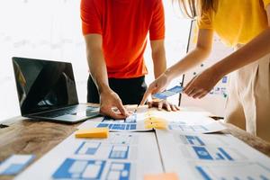 UX developer and ui designer brainstorming about mobile app interface wireframe design with customer breif and color code at modern office. photo