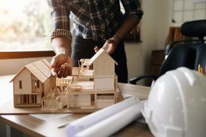 Shot of scale model house on table with architects. Two architects making architectural model in office together. to form a new buildin photo