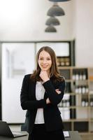 empresaria segura de sí misma mirando a la cámara mientras está de pie. joven empresaria de pie en la sala de juntas de una oficina moderna. foto