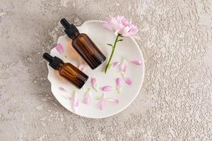 Top view of face and body care products in two dark glass bottles. dropper with cosmetic serum or oil. gray cement background. photo