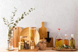 varios tipos de tablas de cortar de madera y recipientes de vidrio para almacenar productos en la encimera de la cocina. artículos ecológicos. fondo de cocina. foto
