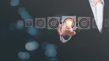 Businessman pointing arrow icon hitting center of dart board target,business goal setting,and concepts that focus on the growth of the organization according to objectives,marketing strategy planning photo