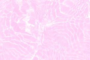 Defocus blurred transparent pink colored clear calm water surface texture with splashes and bubbles. Trendy abstract nature background. Water waves in sunlight with copy space. Pink water shine photo