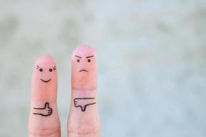 Fingers art of couple. Woman showing thumbs up and man showing thumbs down. Concept of disagreement in family. photo