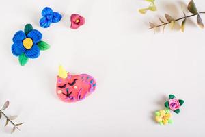 broche en forma de gato y flores de arcilla polimérica sobre un fondo claro. decoración hecha a mano. foto