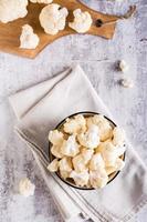 Fresh raw cauliflower in a bowl on the table. Natural antioxidant. Top and vertical view photo