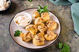 Vegetarian cauliflower buffalo wings and sauce on a plate on the table. Homemade food. photo