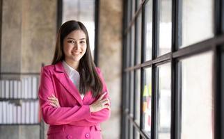 Young smiley attractive, businesswoman using sticky notes in glass wall to writing strategy business plan to development grow to success photo