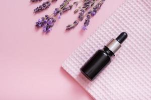 Cosmetic oil in pipette bottle with lavender flowers on colored background. Top view. Flat lay photo