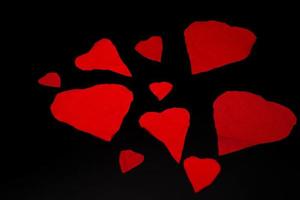 corazones de san valentín rojos rotos en un fondo negro, para la celebración del día de san valentín de febrero foto