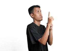 excited asian man wearing black training t-shirt, pointing to copy space. Isolated by white background photo