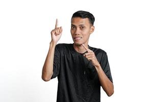 emocionado hombre asiático con camiseta negra de entrenamiento, apuntando al espacio de copia. aislado por fondo blanco foto