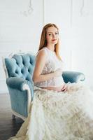 red-haired pregnant young girl in a blue armchair photo