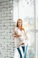 red-haired pregnant girl in a light blouse and blue jeans photo