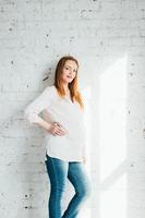 chica embarazada pelirroja con una blusa ligera y jeans azules foto