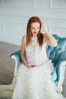 red-haired pregnant young girl in a blue armchair photo