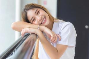 Beautiful and pretty young Asian girl student in Thai university student uniform smiling confidently and looking at camera in university background photo