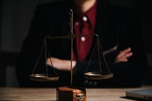 concepto de justicia y derecho. juez masculino en una sala de audiencias con el mazo, trabajando con computadora y teclado de acoplamiento, anteojos, en la mesa a la luz de la mañana foto