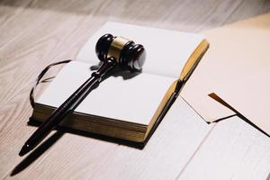 Justice and law concept.Male judge in a courtroom with the gavel, working with, computer and docking keyboard, eyeglasses, on table in morning light photo