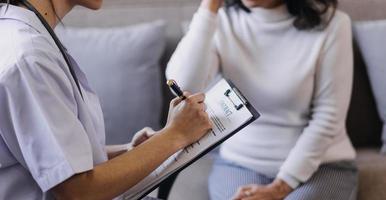 Homecare nursing service and elderly people cardiology healthcare. Close up of young hispanic female doctor nurse check mature caucasian man patient heartbeat using stethoscope during visit photo