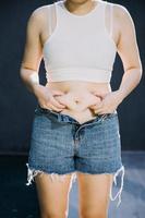 mujer gorda, barriga gorda, gordita, mujer obesa mano sosteniendo grasa abdominal excesiva con cinta métrica, concepto de estilo de vida de dieta de mujer foto