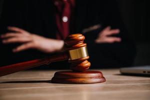 Justice and law concept.Male judge in a courtroom with the gavel, working with, computer and docking keyboard, eyeglasses, on table in morning light photo