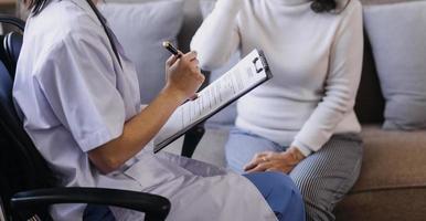 Homecare nursing service and elderly people cardiology healthcare. Close up of young hispanic female doctor nurse check mature caucasian man patient heartbeat using stethoscope during visit photo