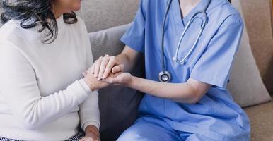 Homecare nursing service and elderly people cardiology healthcare. Close up of young hispanic female doctor nurse check mature caucasian man patient heartbeat using stethoscope during visit photo