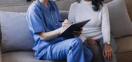 Homecare nursing service and elderly people cardiology healthcare. Close up of young hispanic female doctor nurse check mature caucasian man patient heartbeat using stethoscope during visit photo