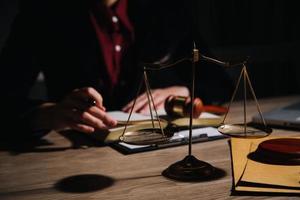 Justice and law concept.Male judge in a courtroom with the gavel, working with, computer and docking keyboard, eyeglasses, on table in morning light photo