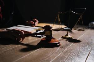 Justice and law concept.Male judge in a courtroom with the gavel, working with, computer and docking keyboard, eyeglasses, on table in morning light photo