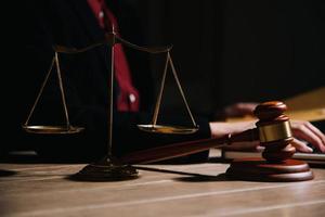 Justice and law concept.Male judge in a courtroom with the gavel, working with, computer and docking keyboard, eyeglasses, on table in morning light photo