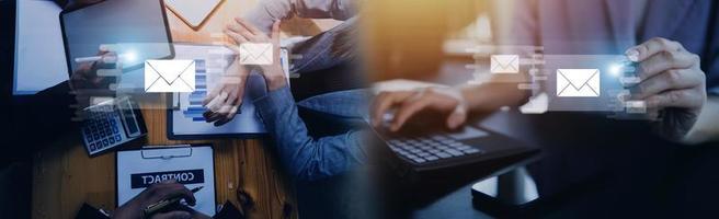 Businessman hands using Laptop typing on keyboard and surfing the internet on office table with email icon, email marketing concept, send e-mail or newsletter, online working internet network. photo