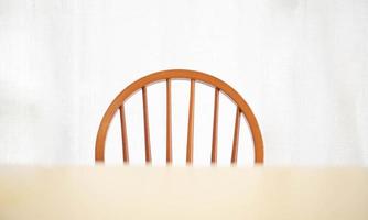 una mesa de comedor de madera vacía y una silla con una lámpara de iluminación que brilla intensamente, una sensación abstracta y solitaria. casa interior muebles objeto foto