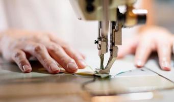 cierre la máquina de coser de mano femenina y tela de algodón en la vieja máquina de coser con estilo vintage. foto