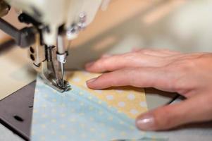 cierre la máquina de coser de mano femenina y tela de algodón en la vieja máquina de coser con estilo vintage. foto